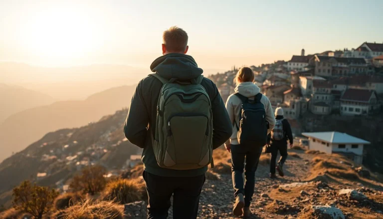 Three hikers in backpacks walk along a rocky mountain trail above a steep, densely built settlement in warm early-morning