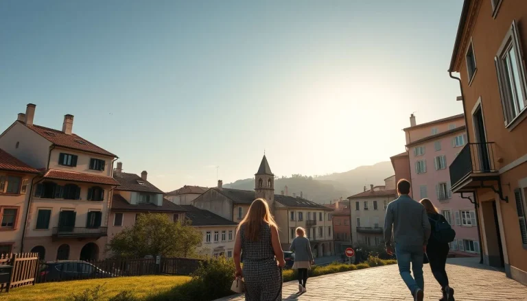 A sunlit European hillside town with pastel buildings, a small church bell tower, mountain scenery, and several pedestrians